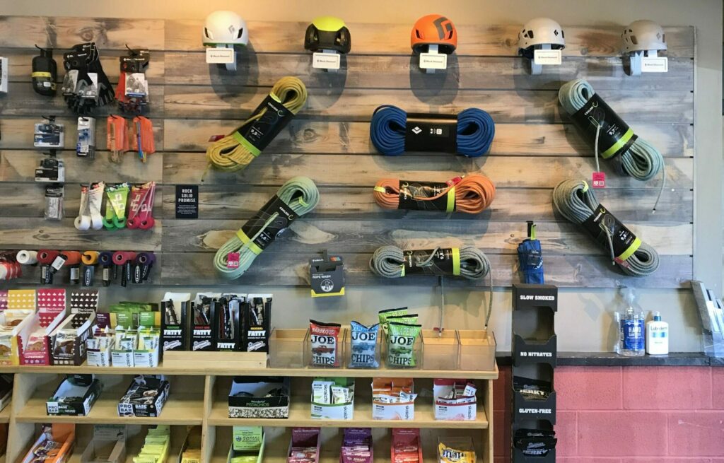 Climbing gear products are displayed on the wall of a Movement gear shop, including helmets, ropes, food, and climbing accessories